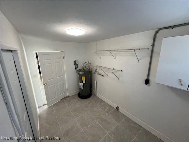 laundry room with electric water heater and cabinets