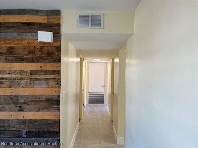 hall featuring light tile patterned floors and wooden walls