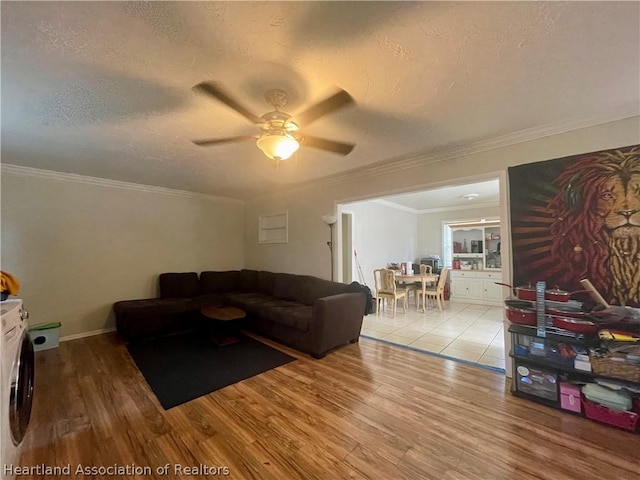 living room featuring a textured ceiling, washer / clothes dryer, ceiling fan, and crown molding