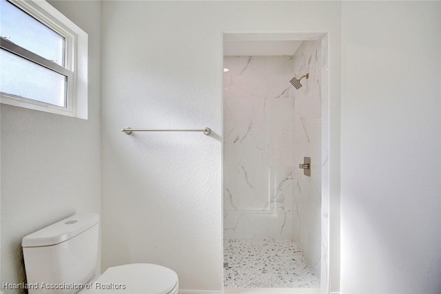 bathroom featuring tiled shower and toilet