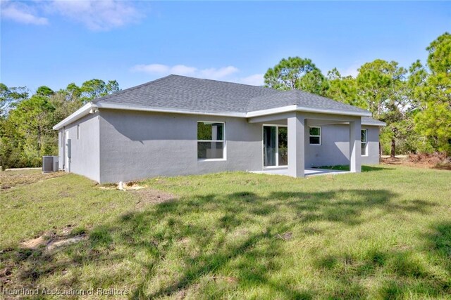 rear view of house with a lawn and central AC