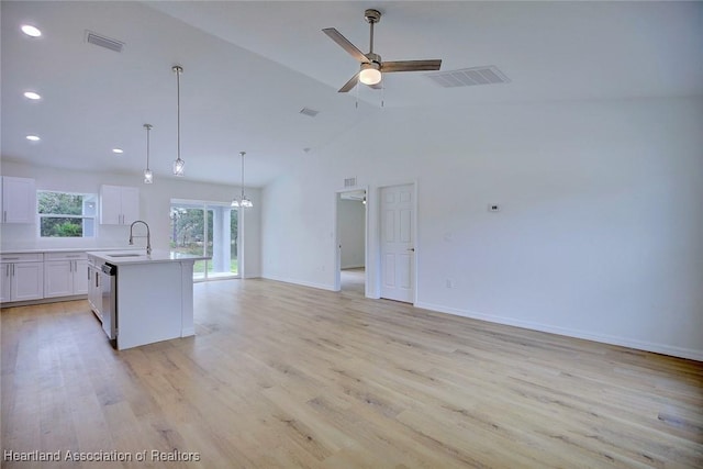 kitchen with pendant lighting, a center island with sink, white cabinetry, and light hardwood / wood-style flooring