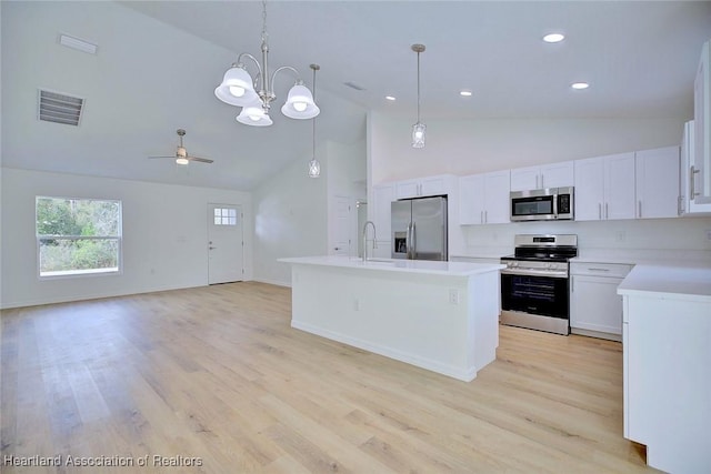 kitchen featuring white cabinetry, a center island, decorative light fixtures, ceiling fan with notable chandelier, and appliances with stainless steel finishes