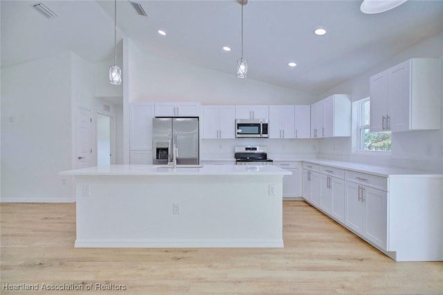 kitchen with white cabinets, appliances with stainless steel finishes, and a center island with sink