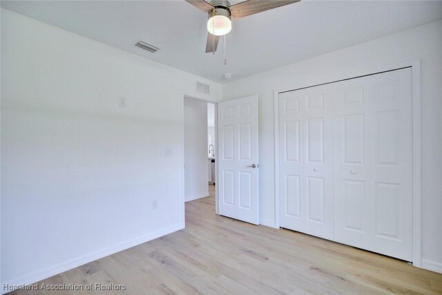 unfurnished bedroom with ceiling fan, a closet, and light wood-type flooring