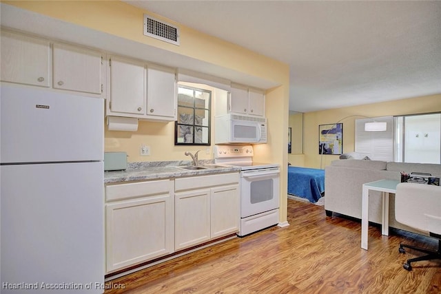 kitchen featuring sink, light hardwood / wood-style floors, white cabinets, and white appliances