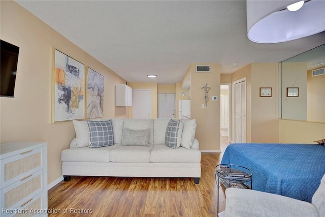 bedroom featuring white refrigerator, connected bathroom, and wood-type flooring
