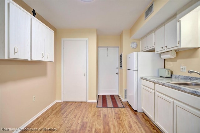 kitchen featuring light wood-type flooring, white cabinets, white fridge, and sink