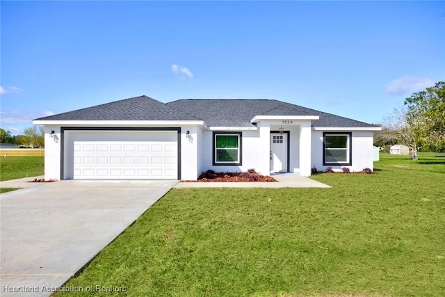 view of front of house featuring a front yard, driveway, an attached garage, and stucco siding