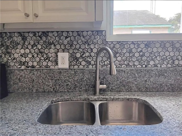 details featuring sink, decorative backsplash, and white cabinets