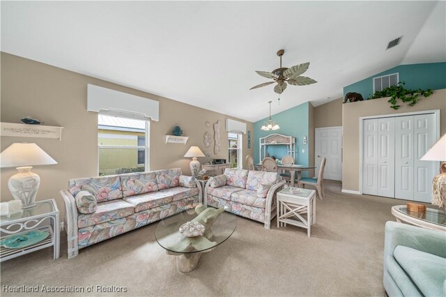 carpeted living room featuring ceiling fan with notable chandelier and lofted ceiling