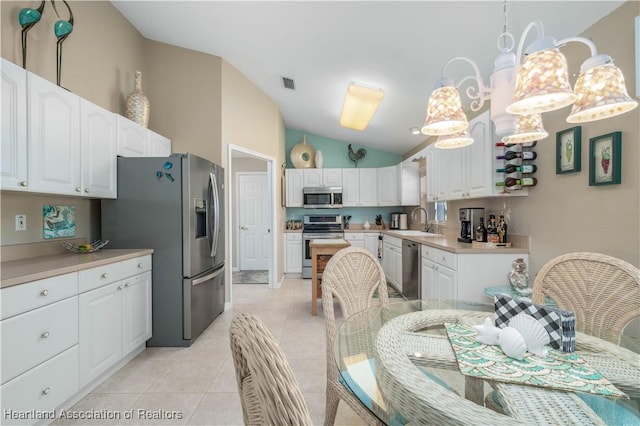 kitchen featuring vaulted ceiling, white cabinetry, sink, pendant lighting, and stainless steel appliances