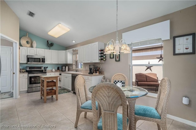 dining room with a notable chandelier, light tile patterned flooring, sink, and lofted ceiling