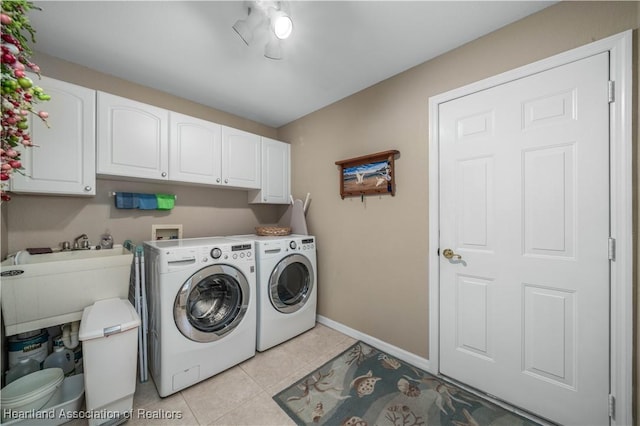 clothes washing area with sink, cabinets, light tile patterned floors, and washing machine and clothes dryer