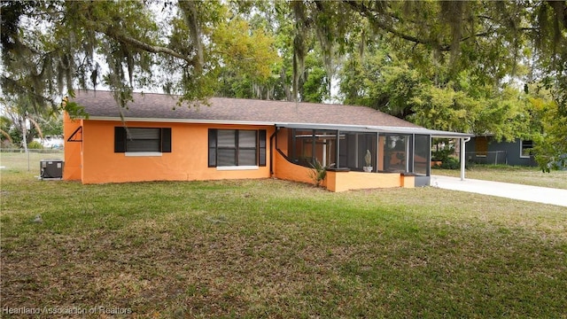 view of front facade featuring central AC unit, a sunroom, driveway, stucco siding, and a front lawn