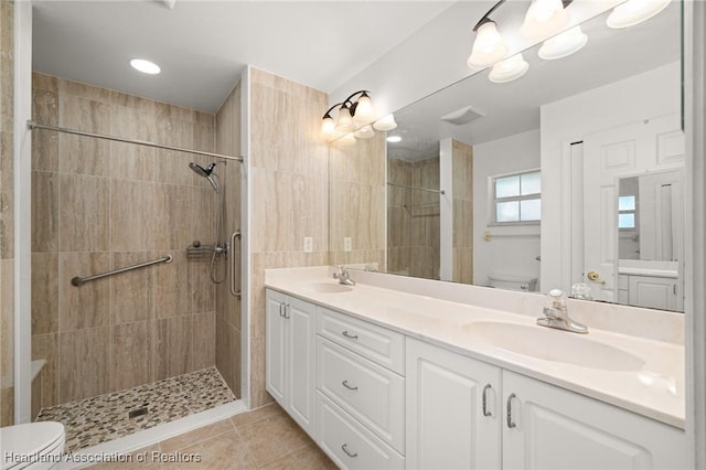 bathroom featuring toilet, tiled shower, and a sink