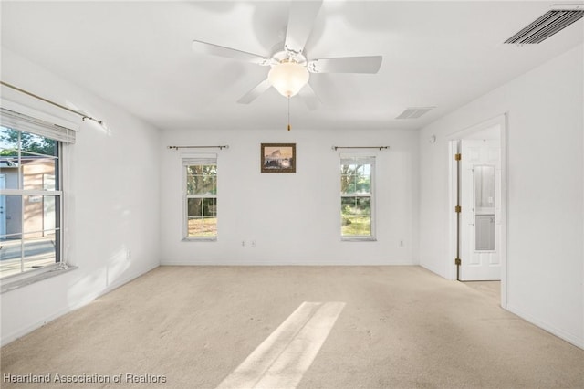 empty room with light colored carpet, visible vents, and a healthy amount of sunlight