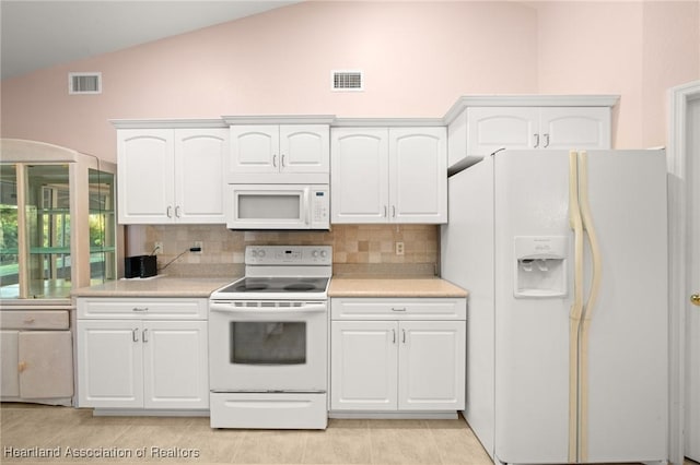 kitchen with light countertops, lofted ceiling, white appliances, and visible vents