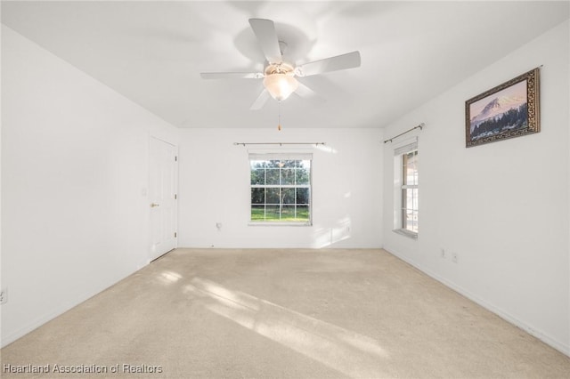 carpeted spare room featuring a ceiling fan