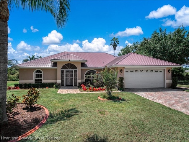 mediterranean / spanish-style home featuring metal roof, a front yard, decorative driveway, an attached garage, and stucco siding