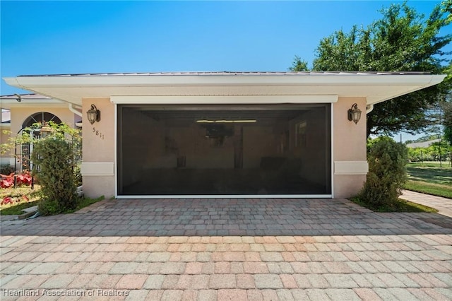 exterior space featuring decorative driveway, an attached garage, and stucco siding