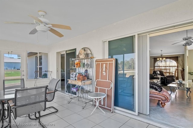 sunroom / solarium featuring ceiling fan with notable chandelier