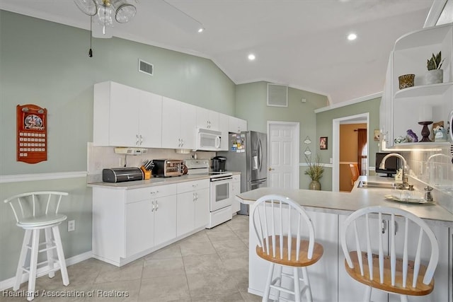 kitchen with a kitchen breakfast bar, white cabinetry, and white appliances