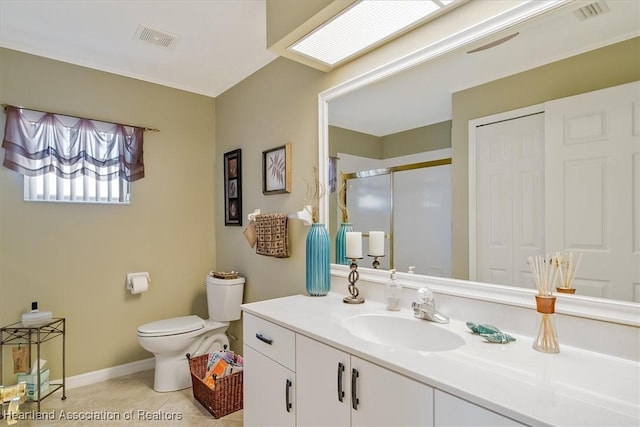 bathroom with a skylight, tile patterned flooring, vanity, an enclosed shower, and toilet