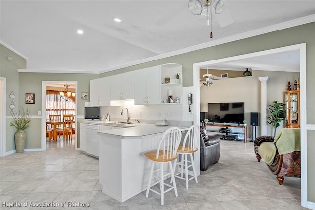 kitchen with sink, white dishwasher, white cabinets, ceiling fan with notable chandelier, and kitchen peninsula