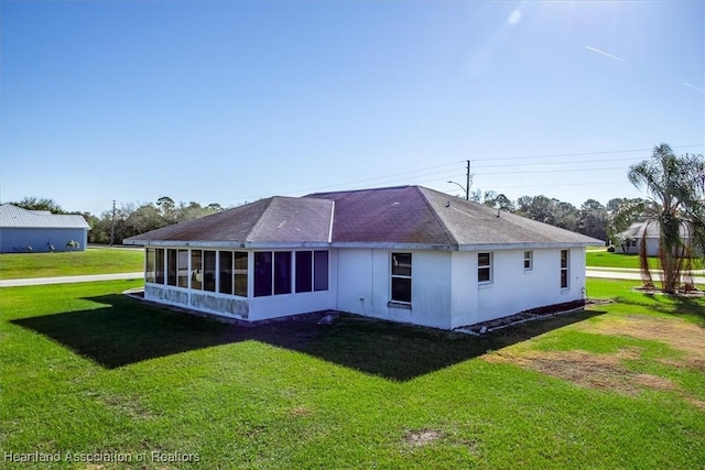 back of property featuring a yard and a sunroom