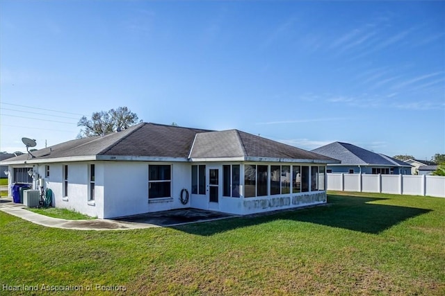 back of property with central AC unit, a lawn, and a sunroom