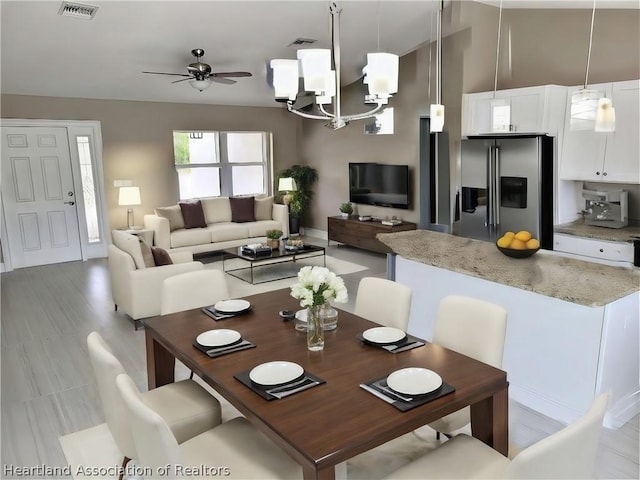 dining room featuring ceiling fan with notable chandelier and light hardwood / wood-style flooring