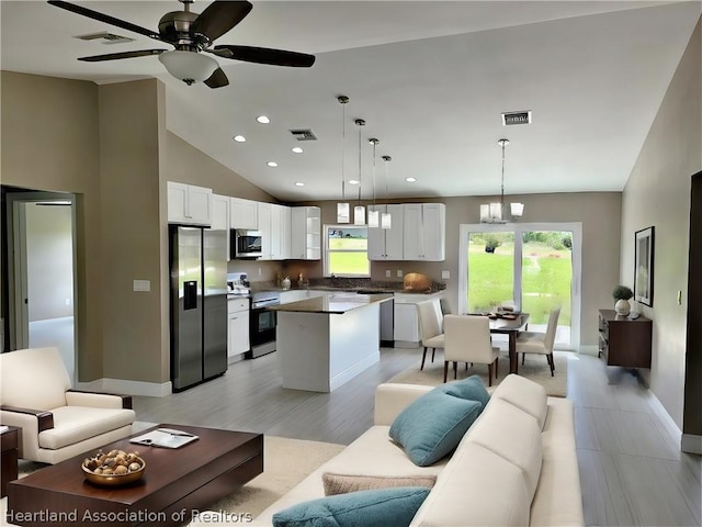 kitchen featuring appliances with stainless steel finishes, decorative light fixtures, a kitchen island, and white cabinetry