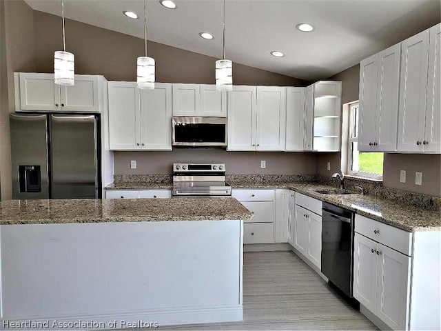 kitchen featuring stainless steel appliances, vaulted ceiling, sink, decorative light fixtures, and white cabinets