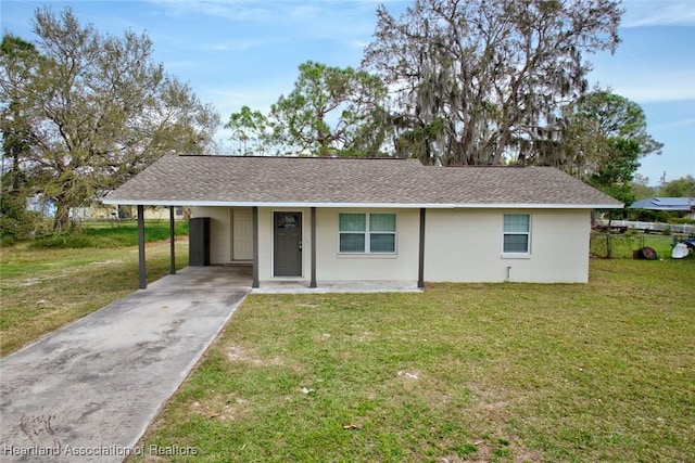 ranch-style house featuring a carport, a front yard, a shingled roof, and driveway