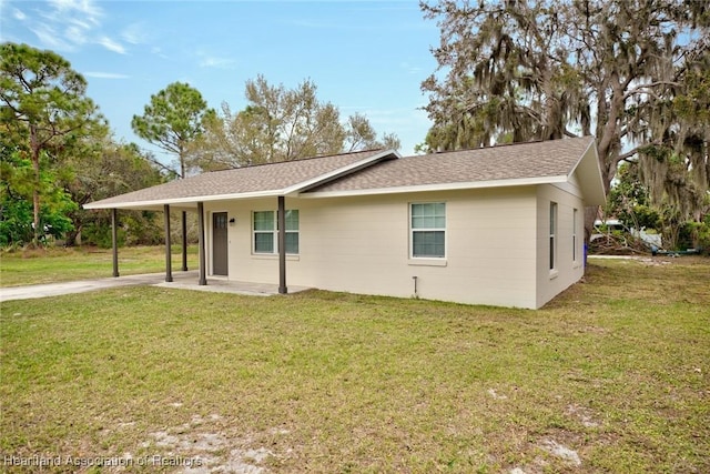 exterior space with a carport, driveway, a front lawn, and a shingled roof