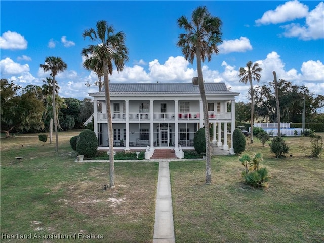 view of front facade featuring a front yard, metal roof, and a balcony