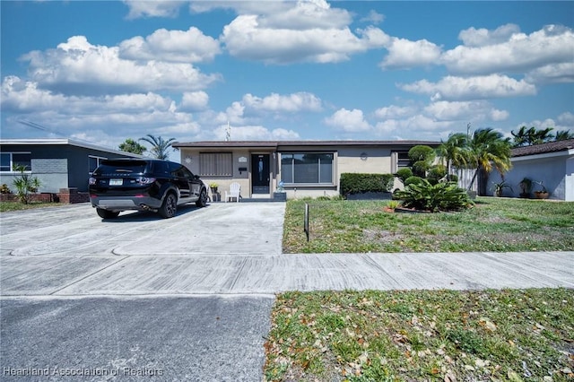 ranch-style house with driveway, stucco siding, and a front yard