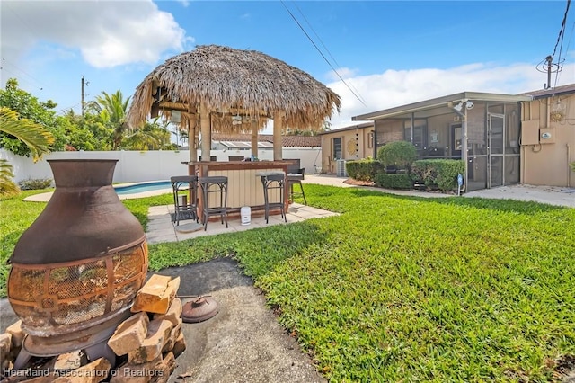 view of yard with outdoor dry bar, a fenced backyard, a sunroom, and a fenced in pool