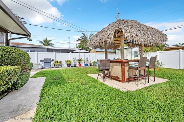 view of yard featuring outdoor dry bar, a patio area, a shed, a fenced backyard, and an outdoor structure