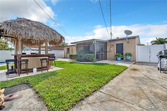 view of yard with outdoor dry bar, a sunroom, fence, and a gate