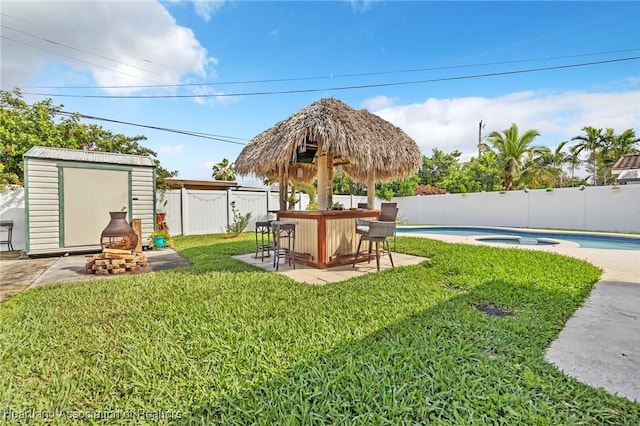 view of yard with a fenced in pool, a fenced backyard, outdoor dry bar, a storage unit, and an outdoor structure