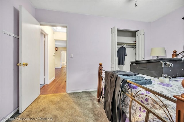 bedroom with light carpet, baseboards, and a closet