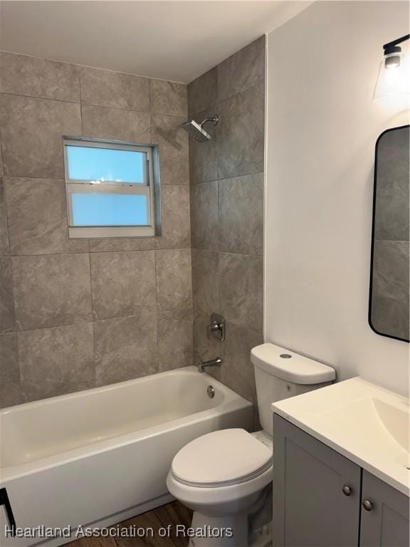 full bathroom with tiled shower / bath, vanity, and toilet