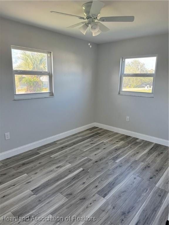 empty room with ceiling fan, a healthy amount of sunlight, and wood-type flooring