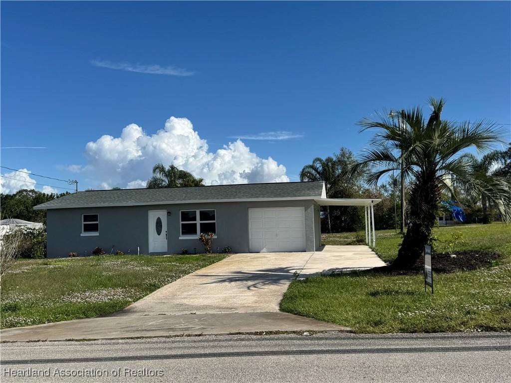 245 Hallmark Ave, Lake Placid, FL 33852 - single story home with a garage, concrete driveway, a front lawn, and stucco siding