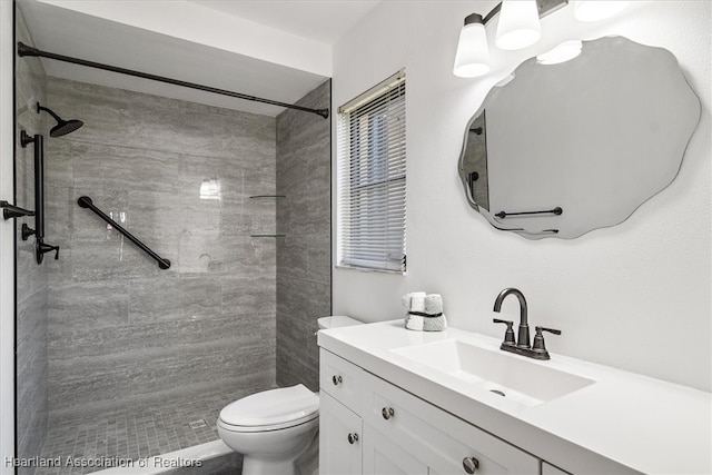 bathroom featuring toilet, vanity, and a tile shower