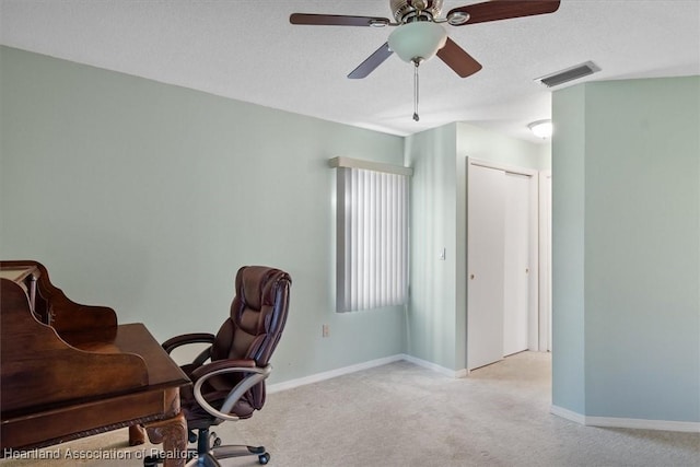 office featuring a ceiling fan, baseboards, visible vents, carpet floors, and a textured ceiling