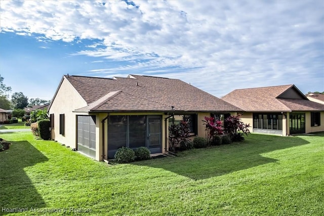 rear view of property with a lawn, a sunroom, and stucco siding