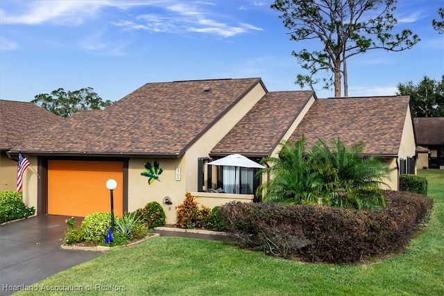 view of front of property featuring an attached garage, a shingled roof, a front yard, stucco siding, and driveway